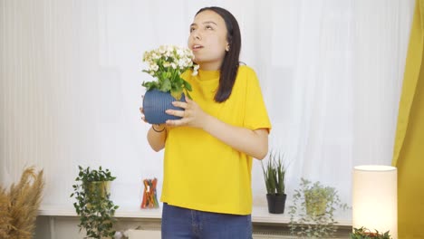 Young-woman-smelling-pot-flower-at-home.
